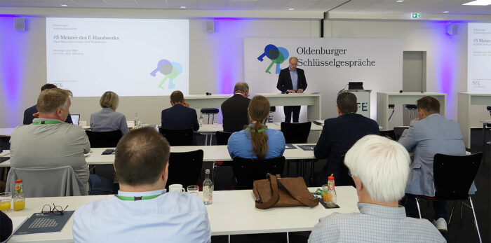 Ein Referent spricht bei den „Oldenburger Schlüsselgesprächen“ im Bundestechnologiezentrum für Elektro- und Informationstechnik (BFE) zu den Teilnehmern. Im Hintergrund ist eine Präsentationsfolie mit dem Veranstaltungstitel „#5 Meister des E-Handwerks“ zu sehen.