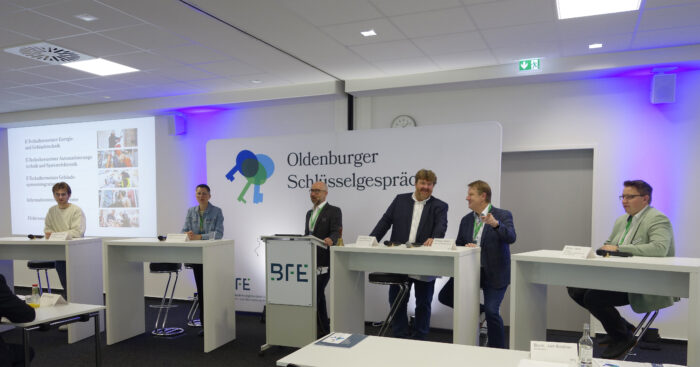 Podiumsdiskussion der „Oldenburger Schlüsselgespräche“ im Bundestechnologiezentrum für Elektro- und Informationstechnik (BFE). Fünf Referenten und ein Moderator sitzen auf einer Bühne an Stehtischen und diskutieren.